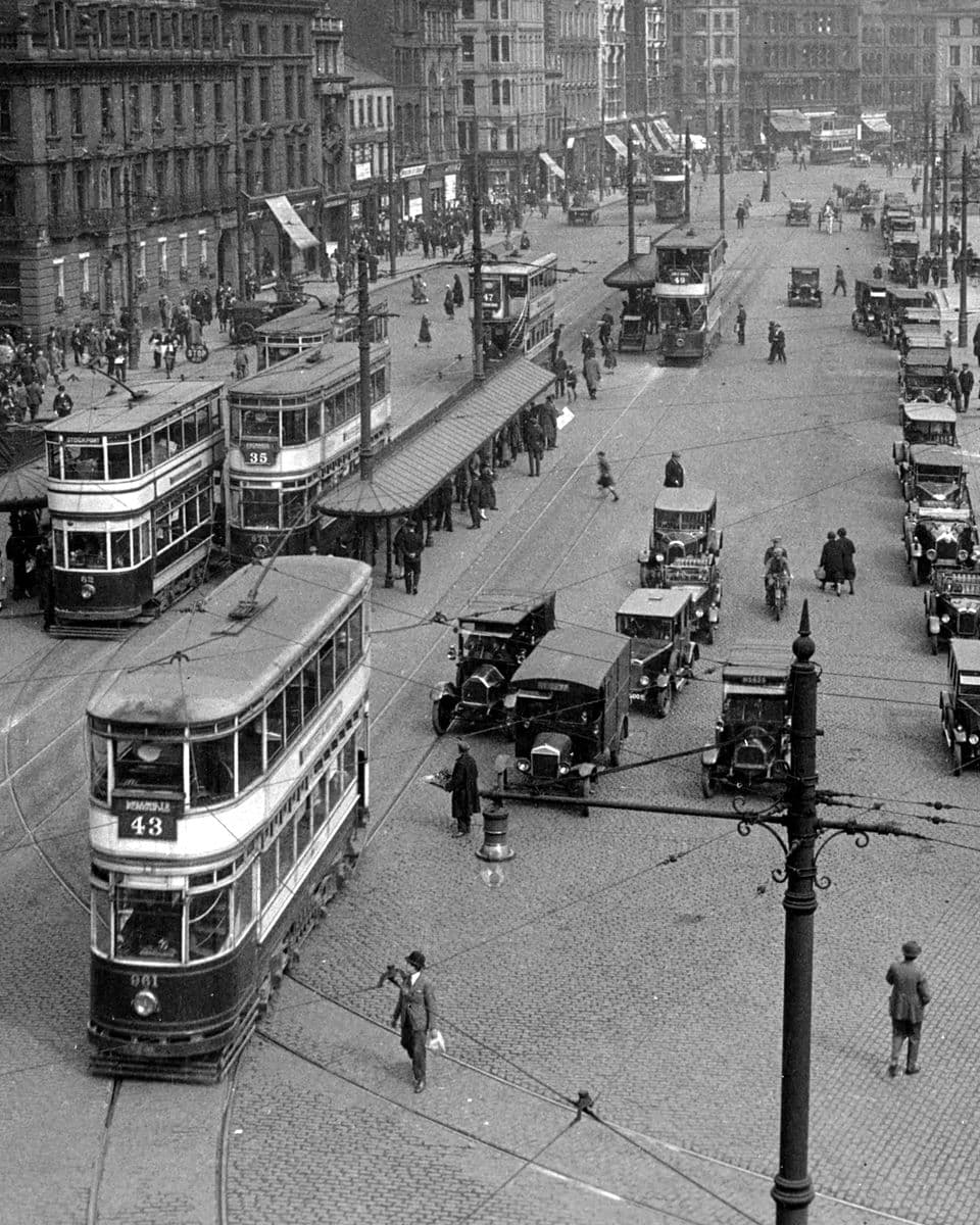 Piccadilly, Manchester, in 1927: double-decker trams, motor vans, and people crossing a busy cobbled street.