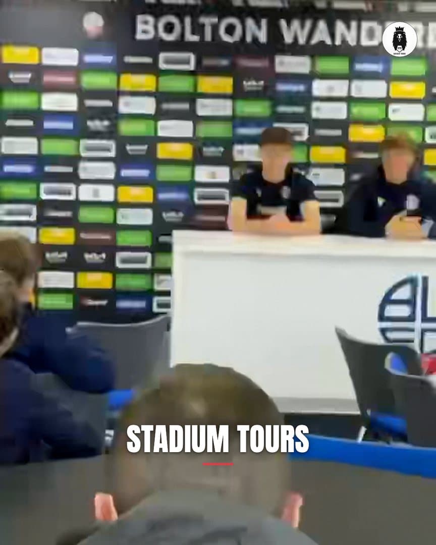 Cover frame of the 15 second tour film: young players at a club press table under the Bolton Wanderers backdrop, with the words Stadium Tours across the bottom.